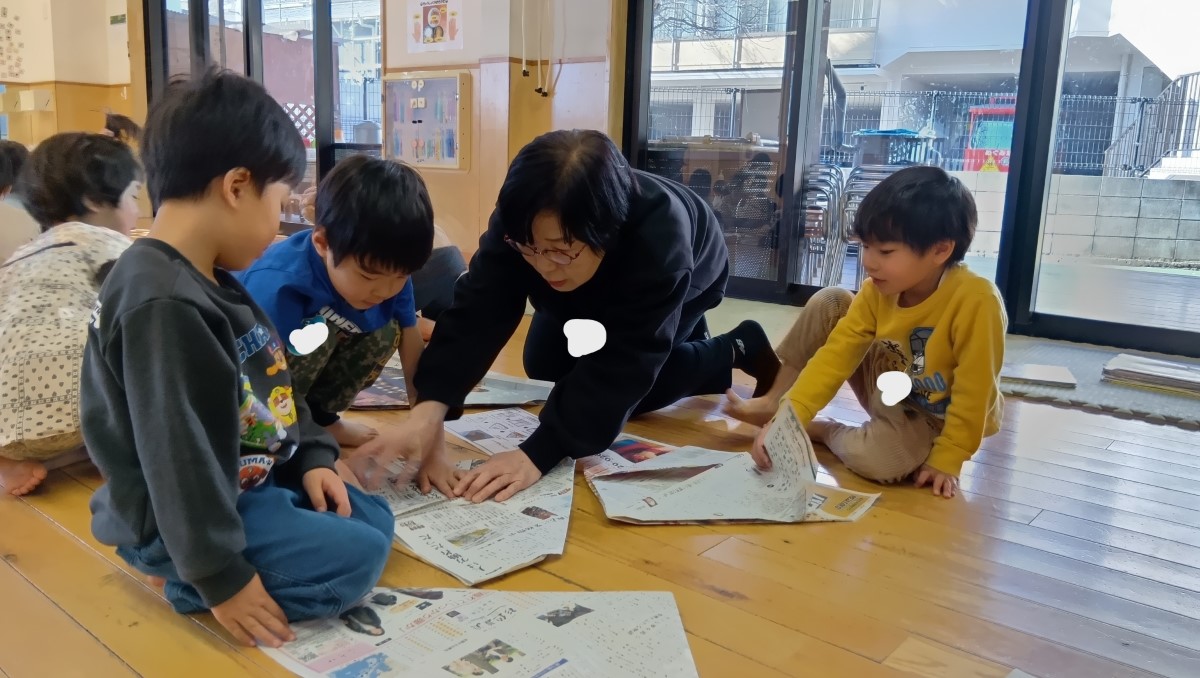 新聞紙で兜を折る子どもたち