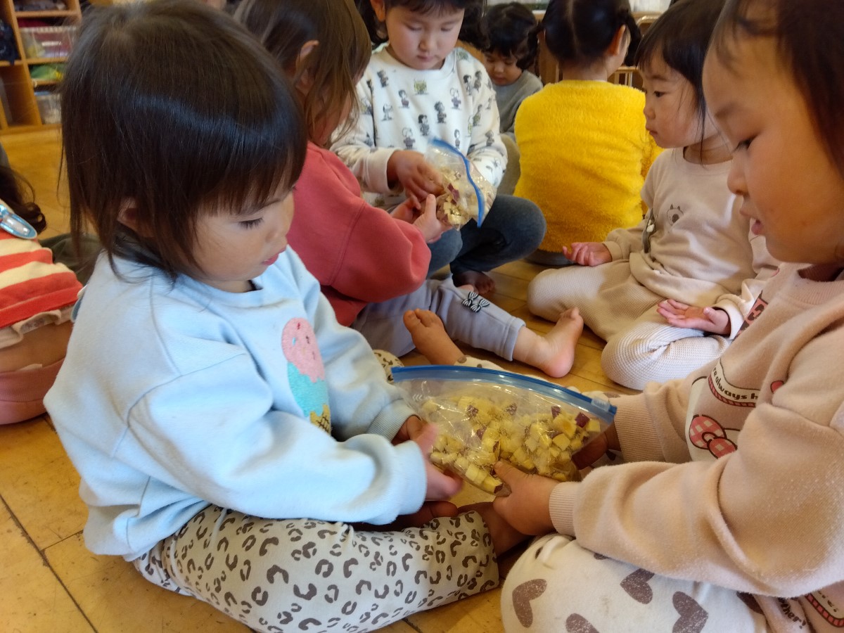 ポリ袋でサツマイモと材料を混ぜる子どもたち