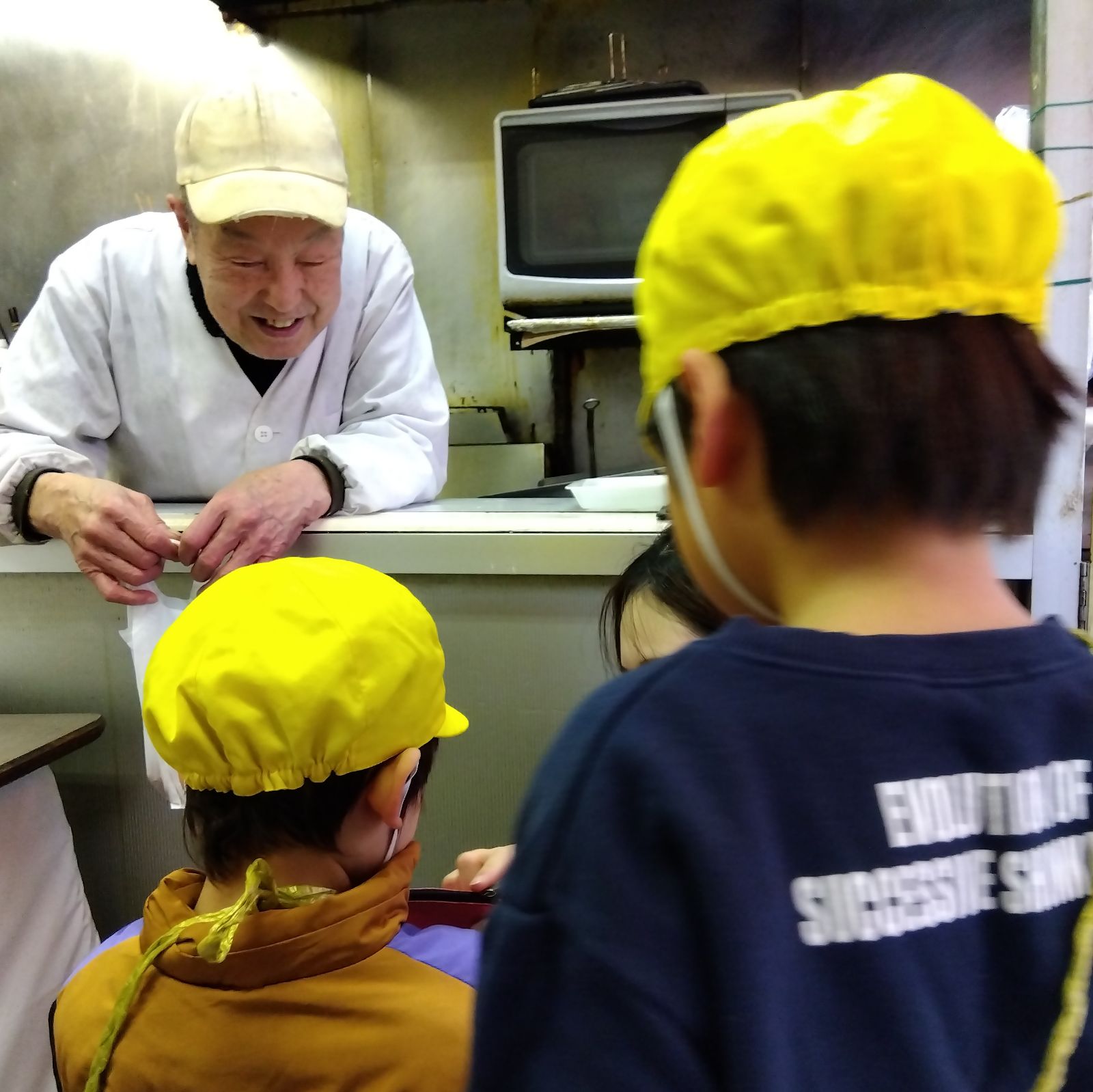 肉屋の定員と話す子どもたち