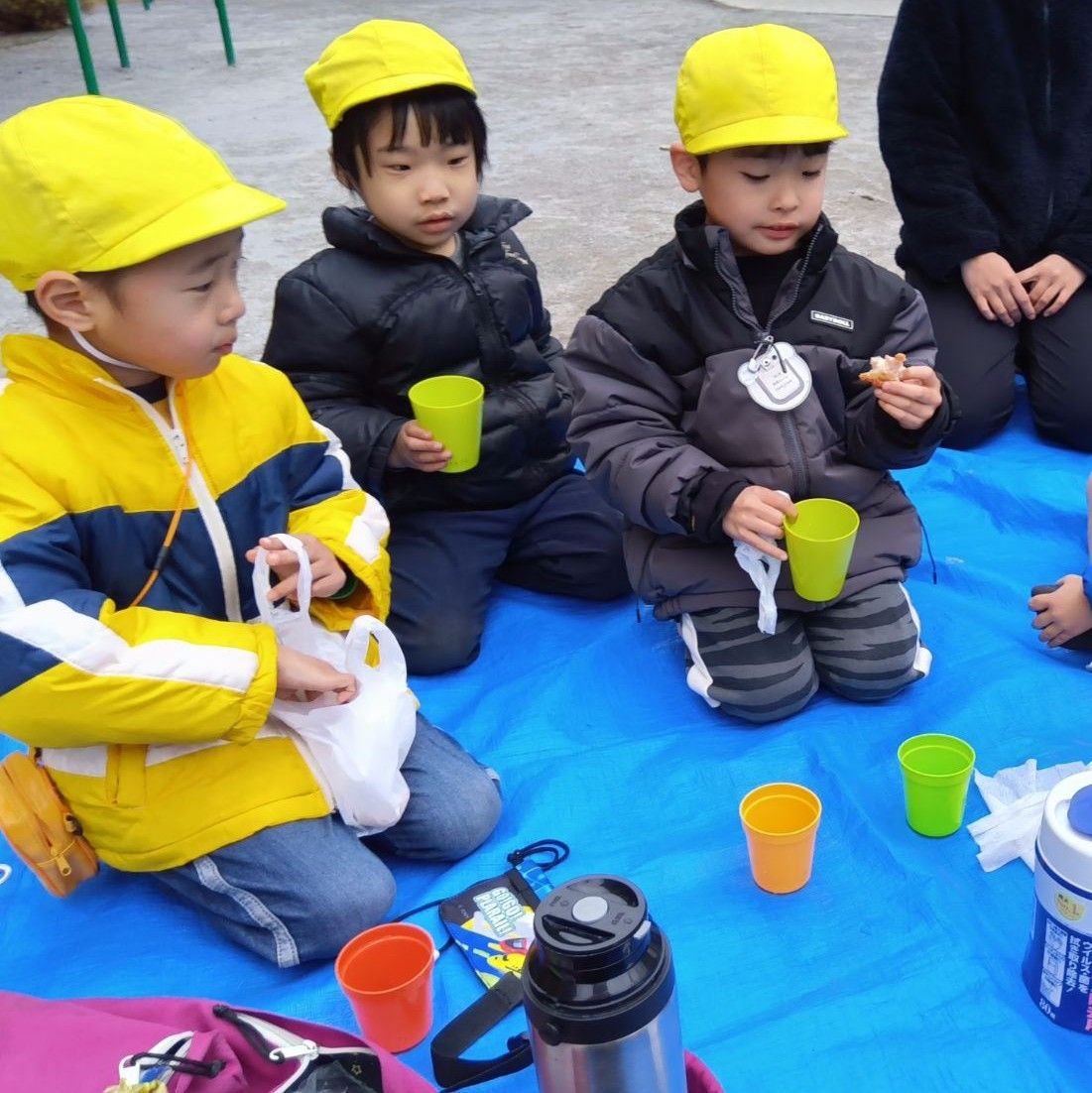 公園でブルーシートをひいて唐揚げを食べる子どもたち