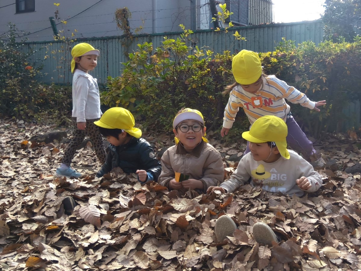 落ち葉に埋もれて遊ぶ子どもたち