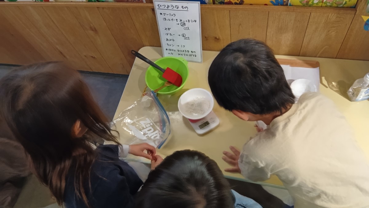 チョコチップスコーンの材料を計る子どもたち