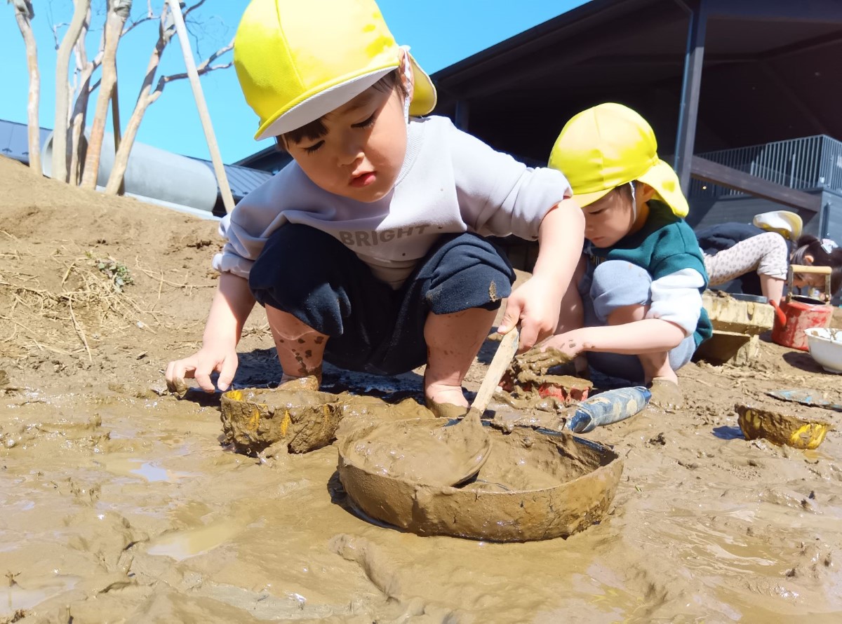 園庭で泥遊びをする子どもたち