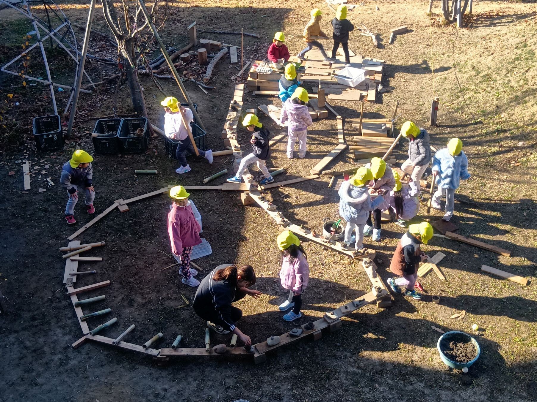 子どもたちが園庭に配置され木材や石で主体的に創作する様子