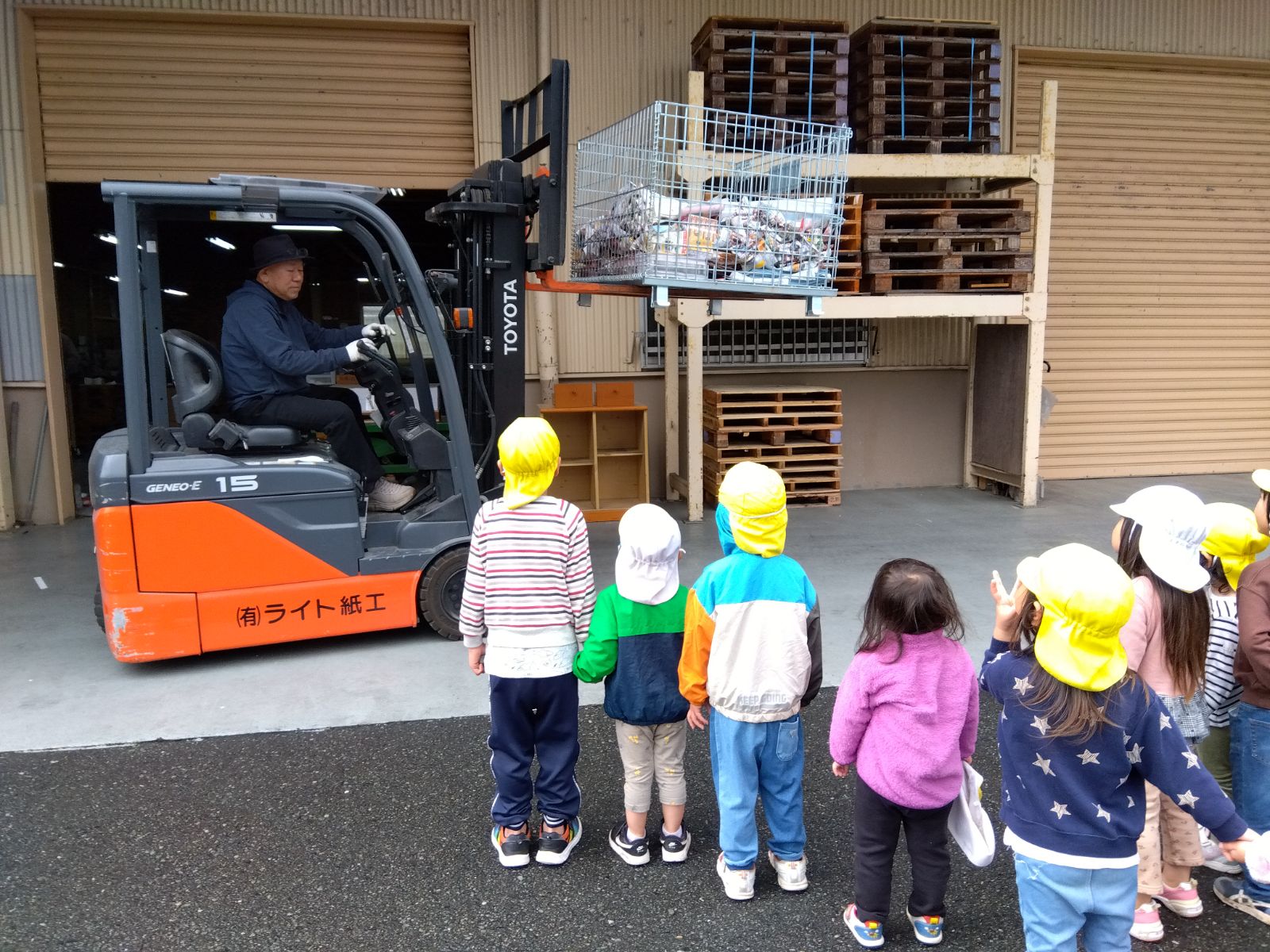 フォークリフトで紙を運ぶ様子を眺める子どもたち