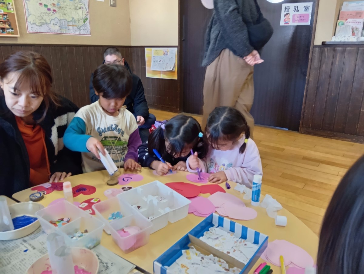 ハート形の紙に絵を描く子どもたち