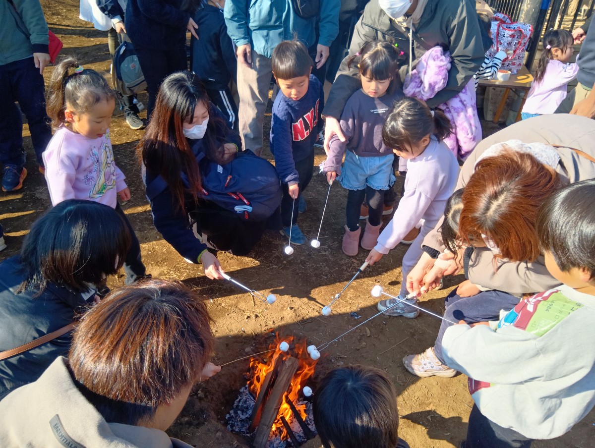 焚き火を囲んでマシュマロを焼く子どもたち