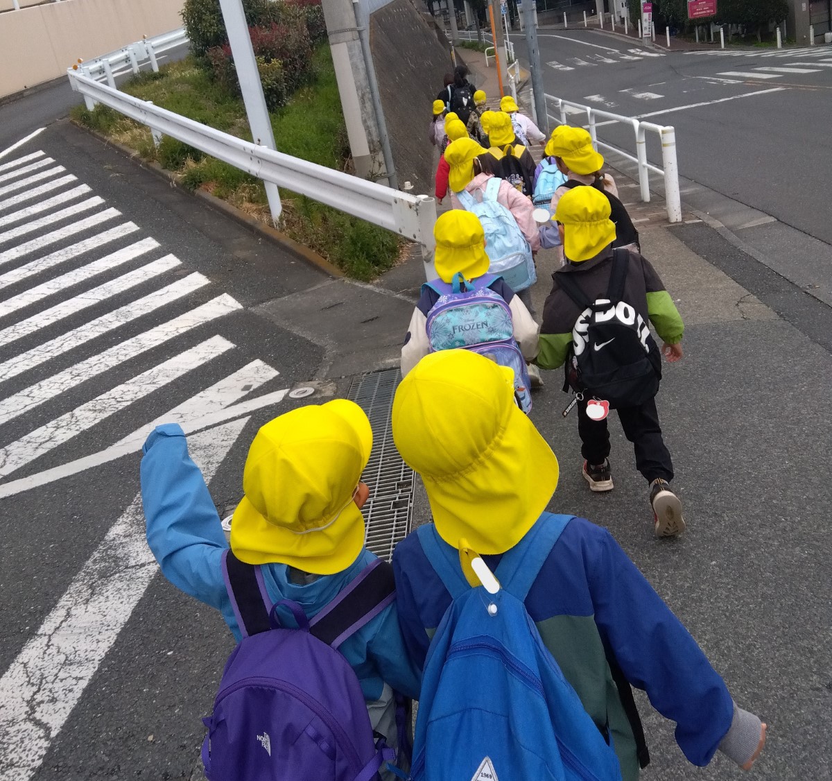 横断歩道を手を挙げて渡る子どもたち