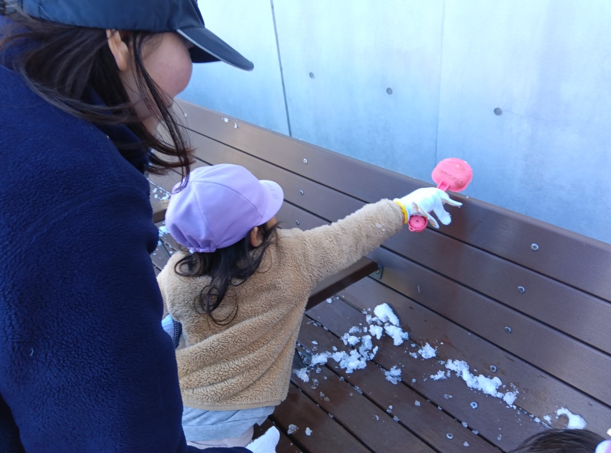 ベンチの雪をきれいにする子ども