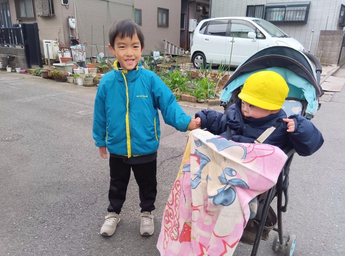 ベビーカーの子どもと手をつなぐ子ども