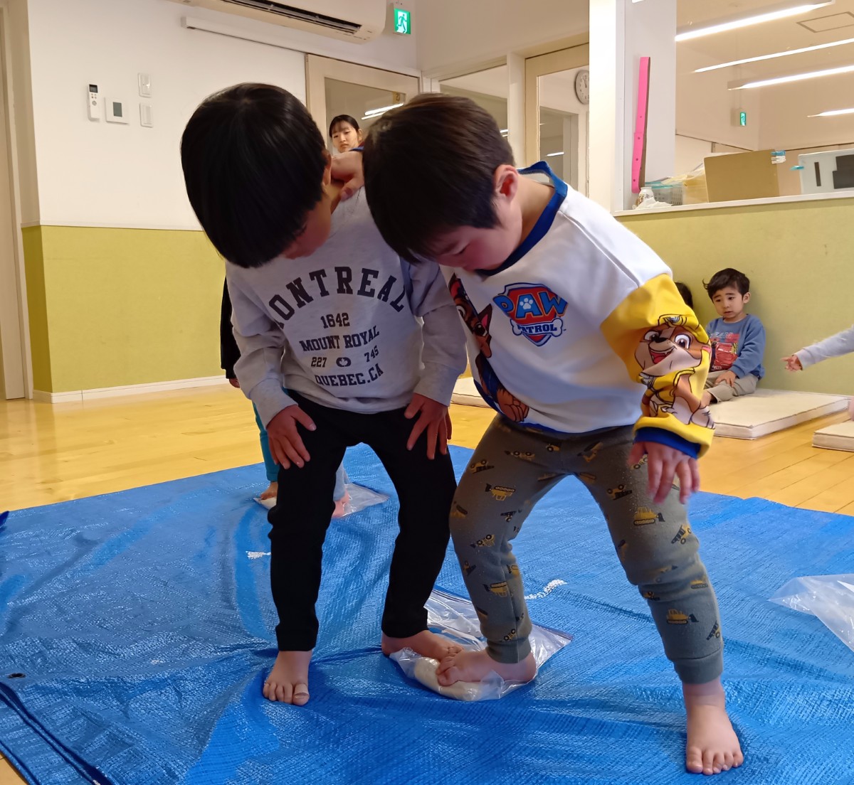 ポリ袋に入ったうどん生地を踏む子どもたち