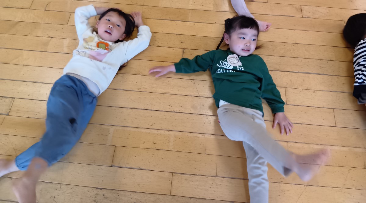 仰向けになって右足を上げる子どもたち