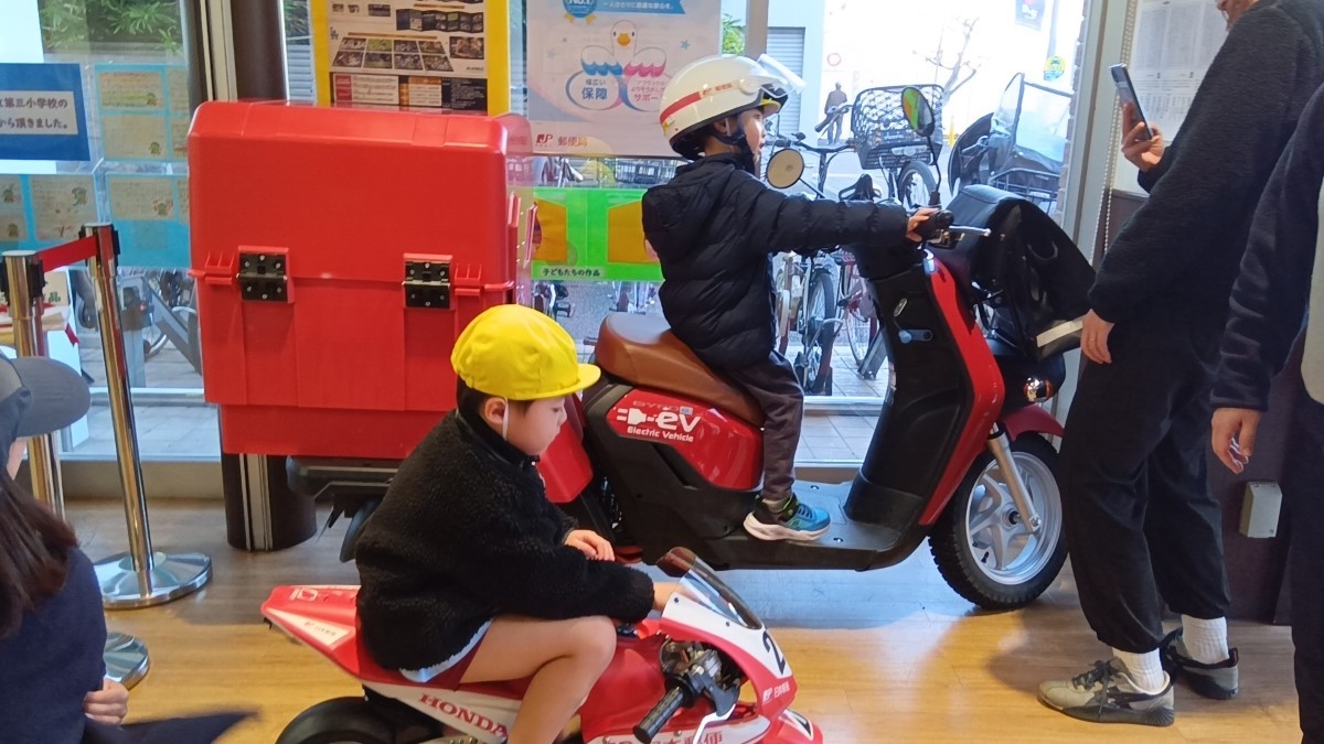 郵便バイクに乗せてもらう子どもたち