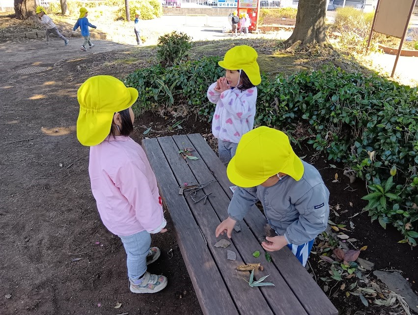 ベンチに落ち葉や木の枝を並べてお店屋さんごっこをする子どもたち