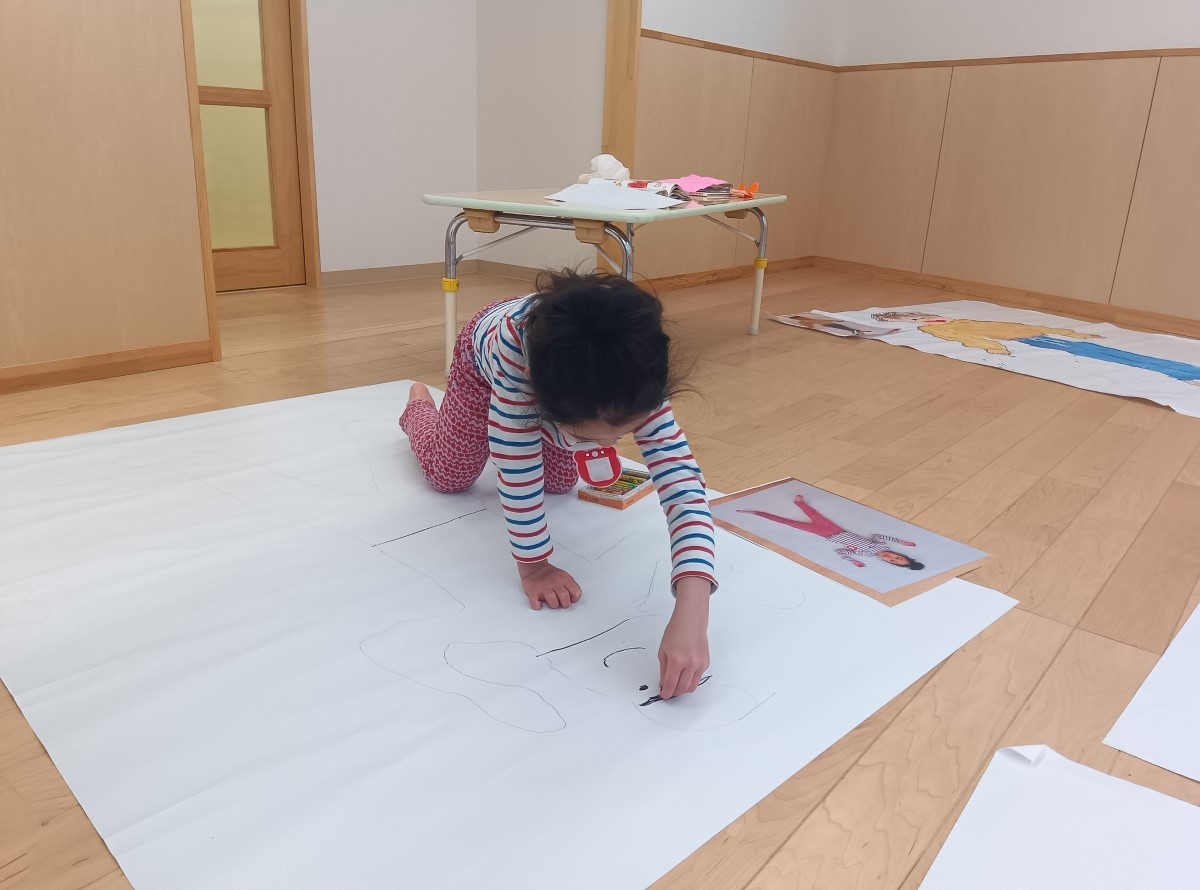 大きな模造紙に自分の絵を描く子ども