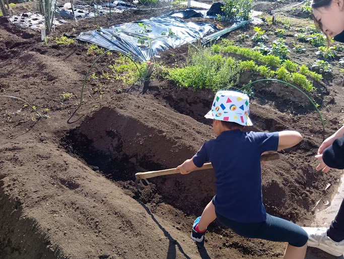 道具を使って畑を耕す子ども