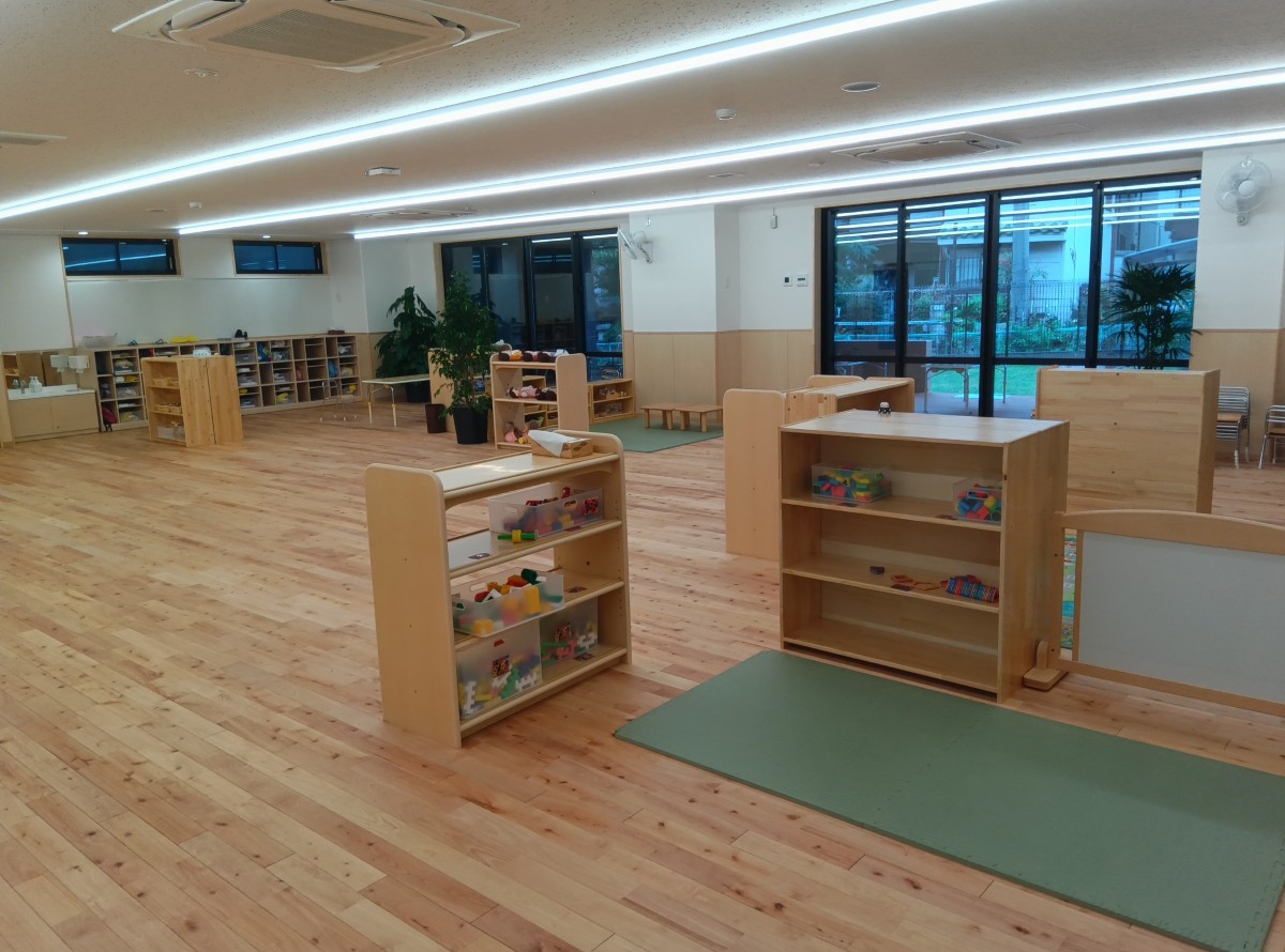 広い保育室は、取り出しやすい棚に玩具が置かれ、コーナー毎に空間が仕切られている