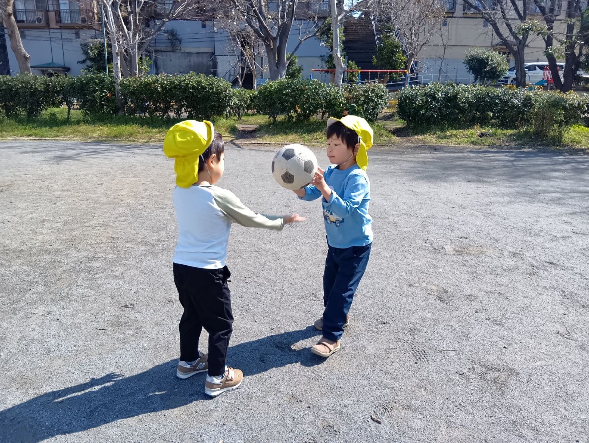 ふたりの子どもが向かい合い、ボールを受け渡している