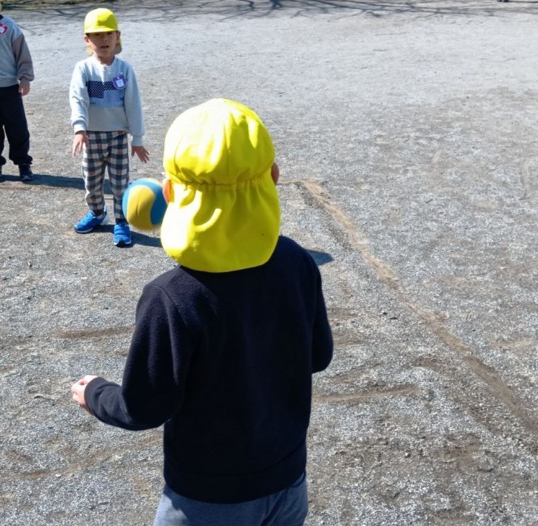 少し離れた距離から、一人のこどもがもう一人の子どもにボールを投げている