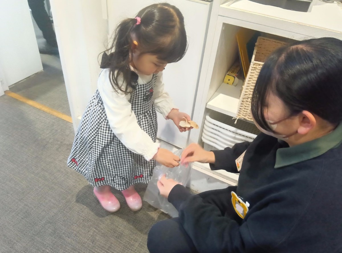大人が袋を開き、子どもが袋に椎茸を入れている。