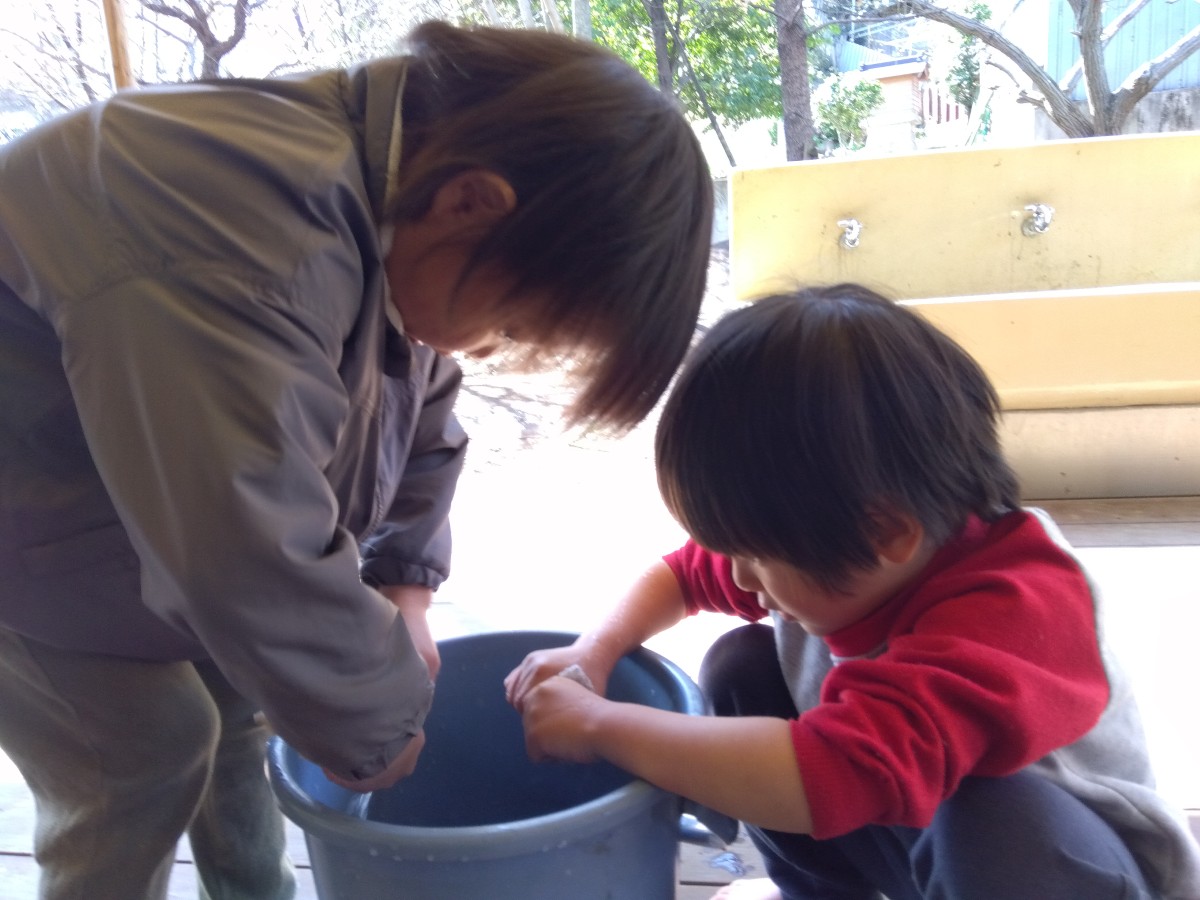 子どもたちがバケツで雑巾を濡らし、雑巾を絞っている
