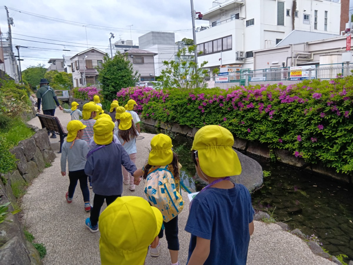 首からカードを下げた子どもたちが手をつないで、川沿いを歩いている。