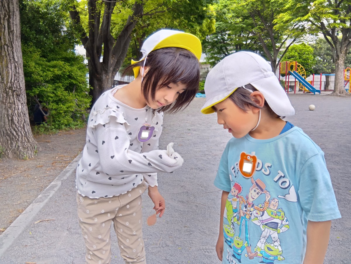 二人の子どもたちが、一人の子どもの手元をじっと見つめている。