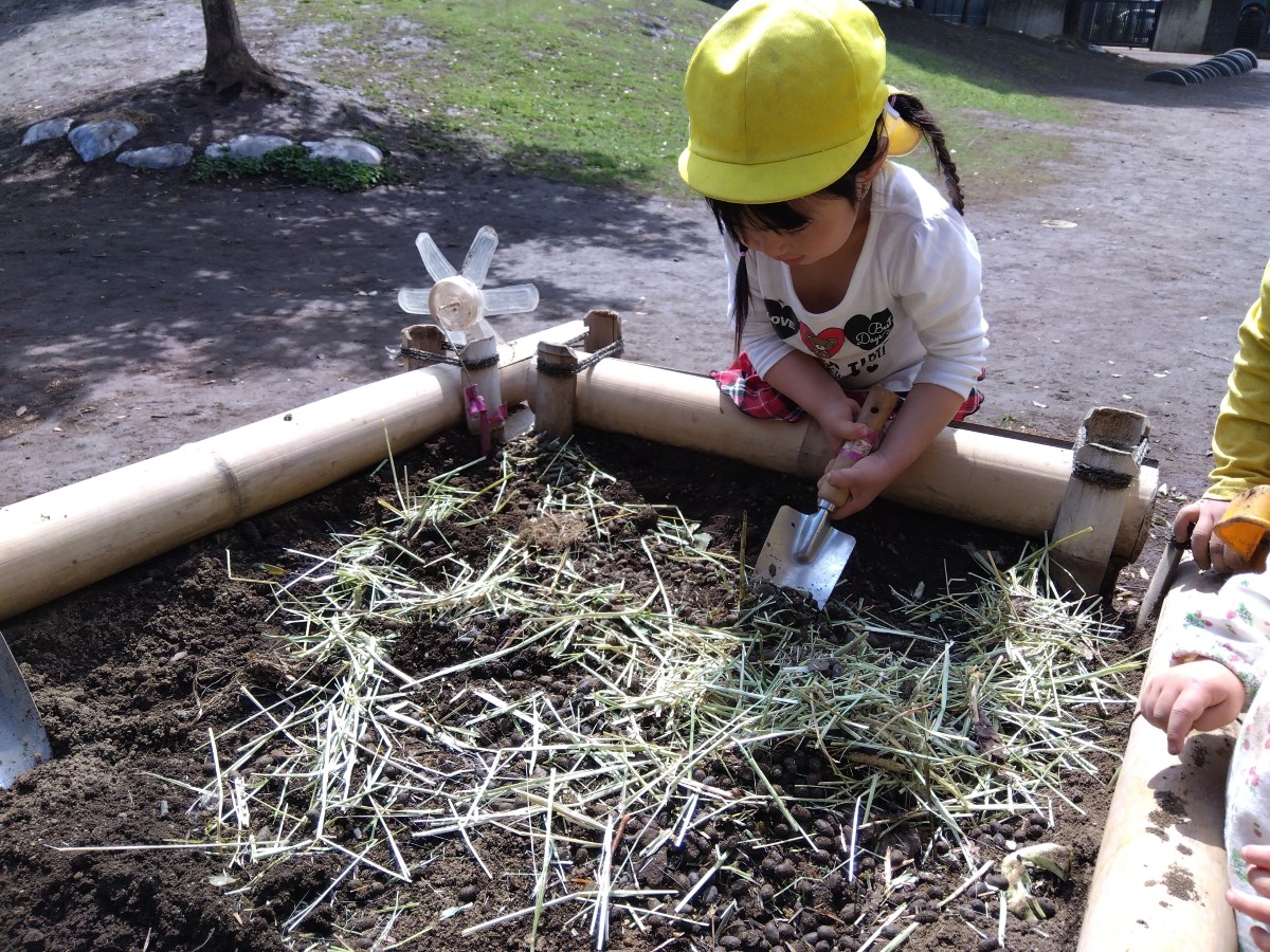 一人の子どもが、両手でシャベルを持って土を掘っている。