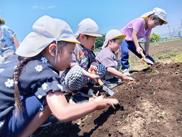 四人の子どもたちは、立ち姿勢、座り姿勢でシャベルを使って土を掘っている。