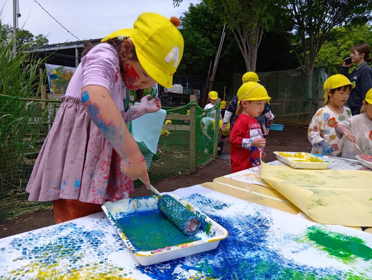 ローラーに絵の具をつける子ども