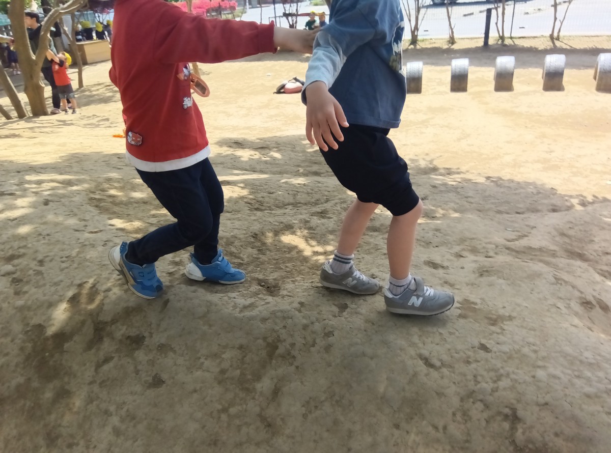園庭遊びで、前にいる子に後ろにいる子は手を伸ばしている。