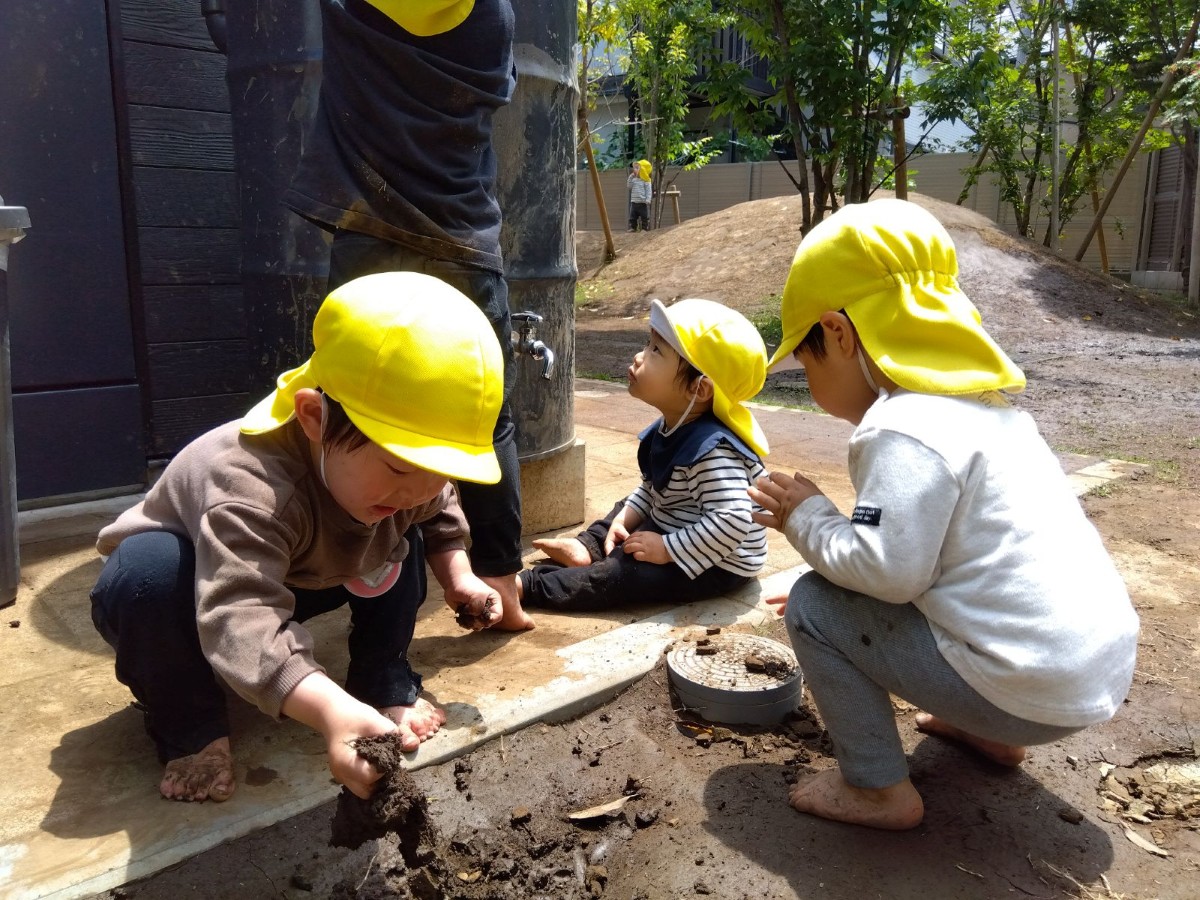 一人の子どもが手足を泥だらけにして、泥をつかんでいる。