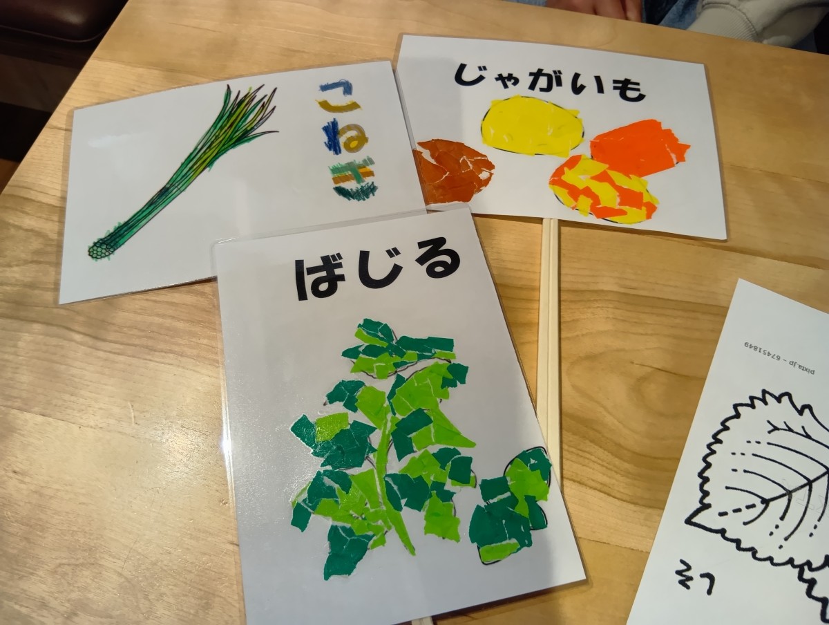貼り絵や塗り絵で作られた野菜の看板が机に置かれている。