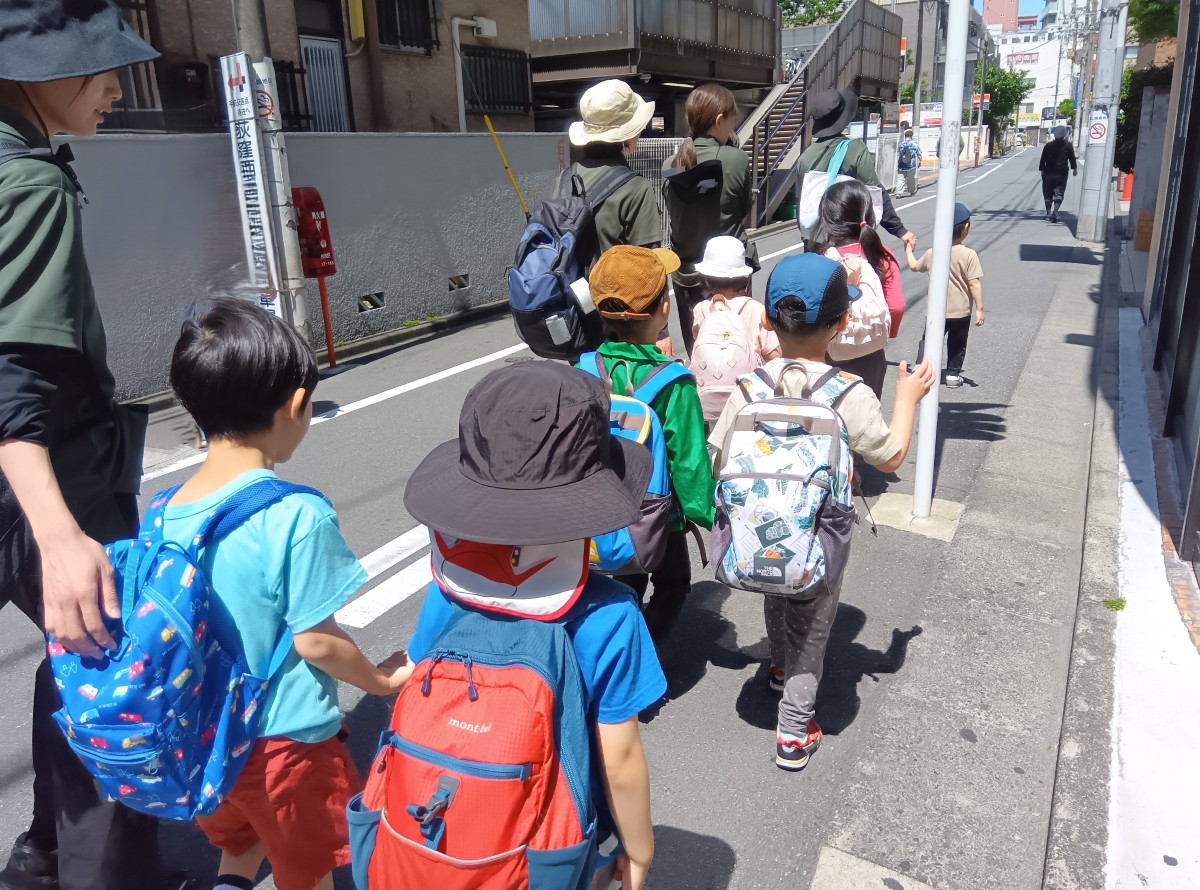 公道を子どもたちが手をつないで列になり歩いている。