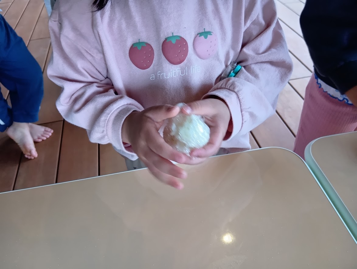 ラップでご飯を包み、ご飯を握って丸めている。