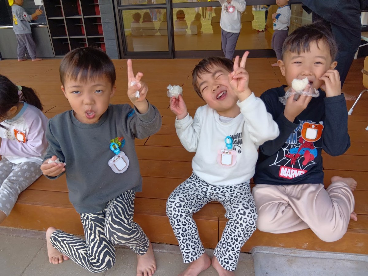 子どもたちは縁側に並んで座り、自ら握ったおにぎりを笑顔で食べている。