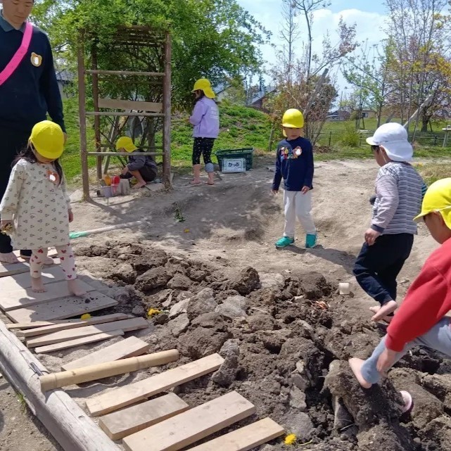 園庭には、子どもたちが作った橋やでこぼこした砂場があり、その上を裸足の子どもたちが歩いている。