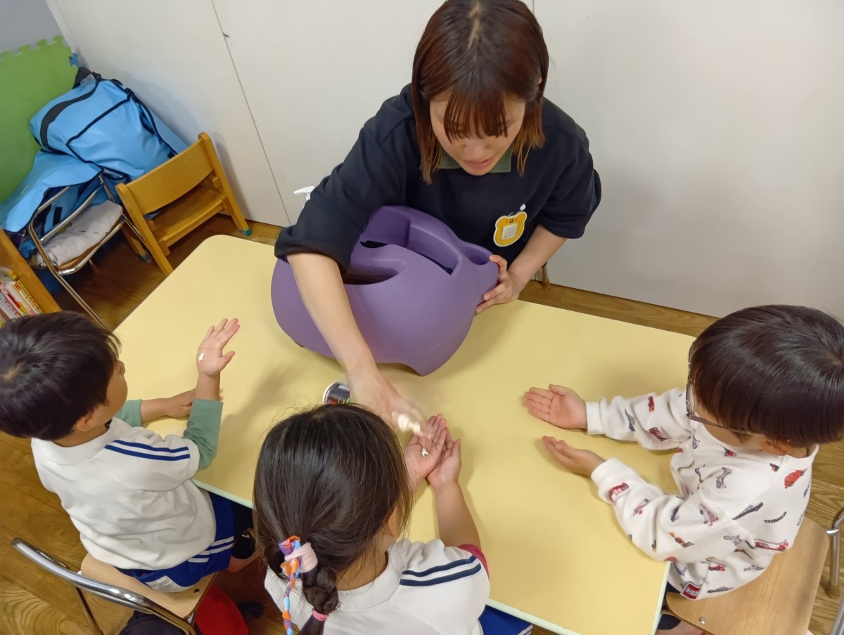 子どもたちは両手の平を出して、大人がローションを着けている。
