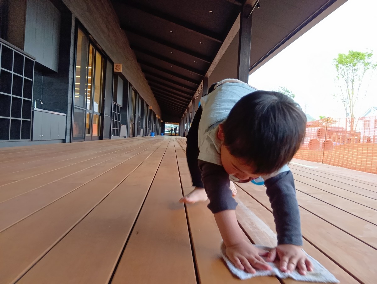縁側で、一人の子どもが腰を高くして雑巾がけをしている。