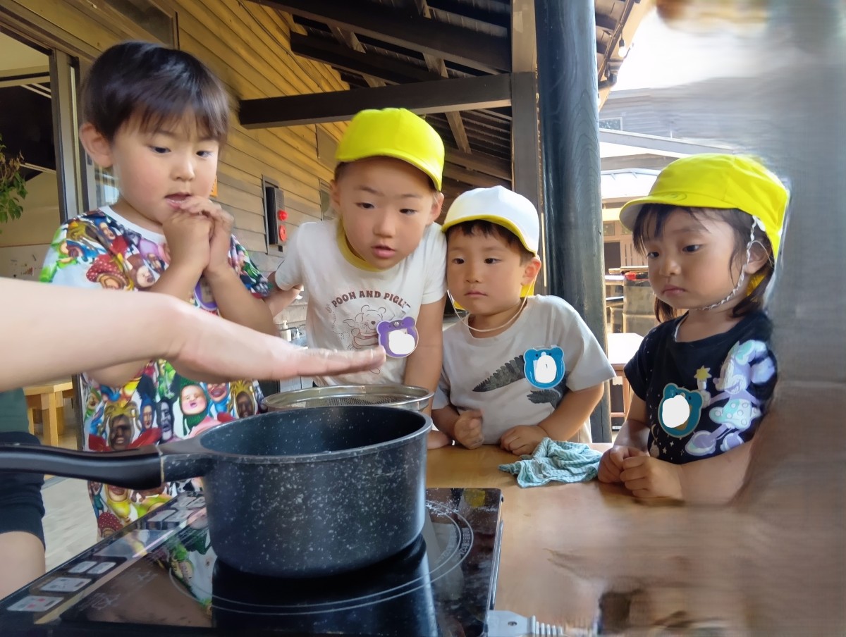 子どもたちは、大人がフライパンの近くに手をかざす姿を真剣な表情で見ている