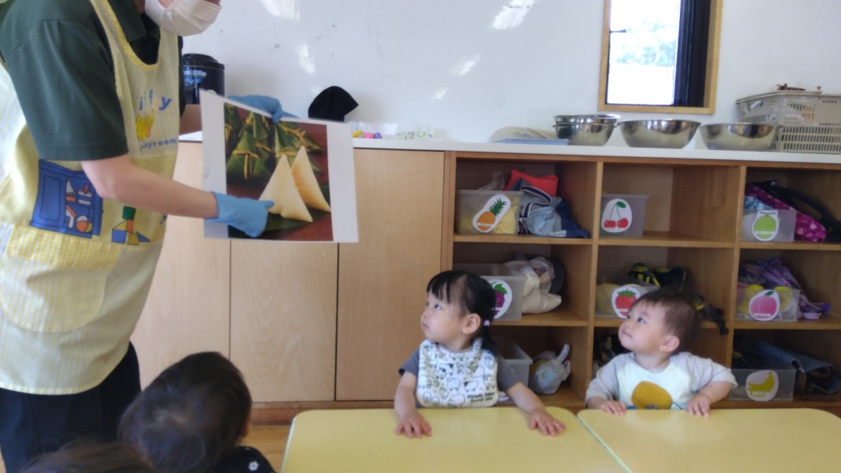 大人がちまきの写真を手に持ち、子どもたちはその写真をじっと見つめている。