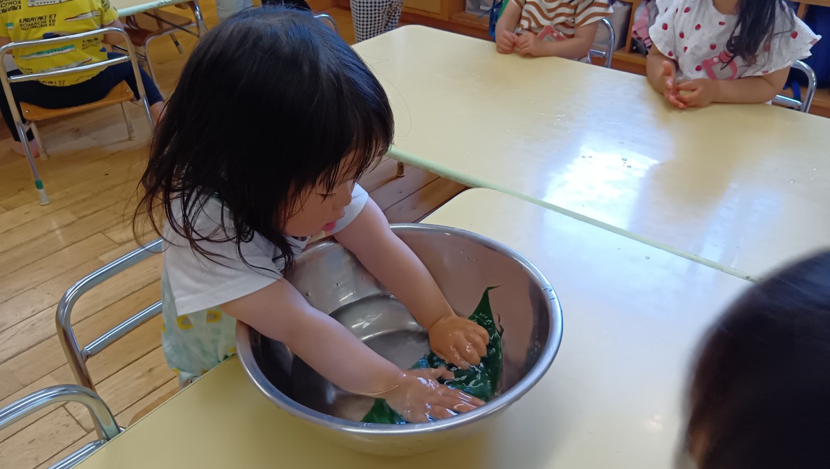 水の入ったボールの中に、子どもが笹の葉を浸して洗っている。