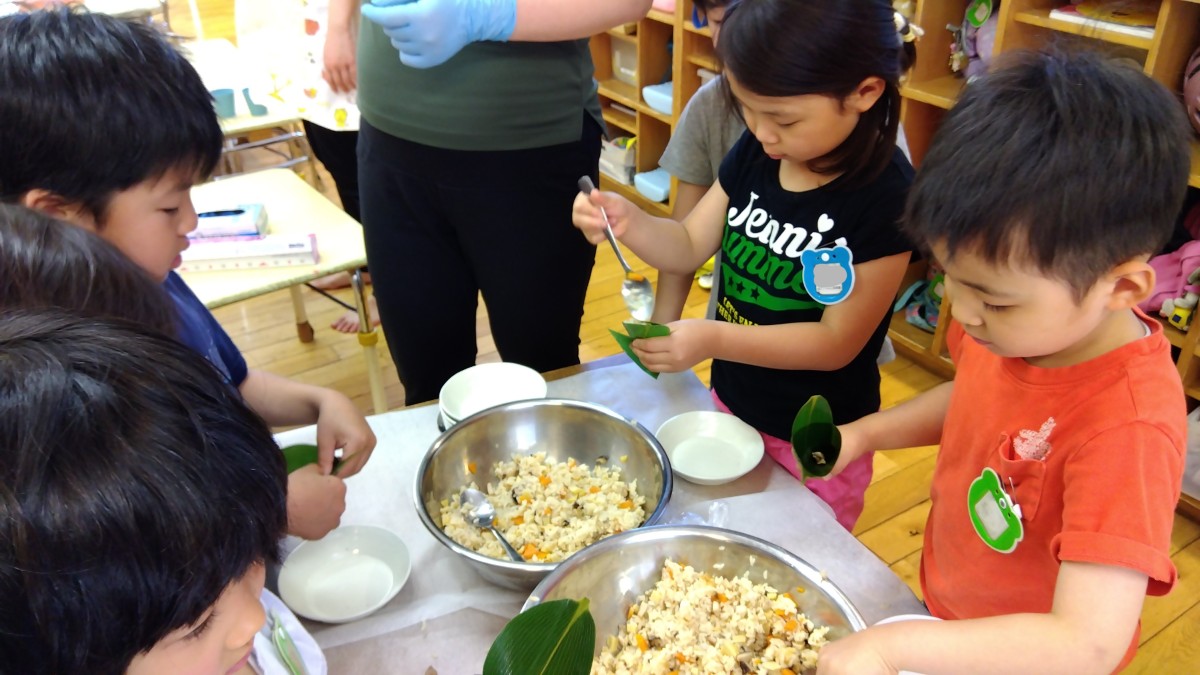 子どもたちはスプーンを使って丸く巻かれた笹の中にご飯を入れている。