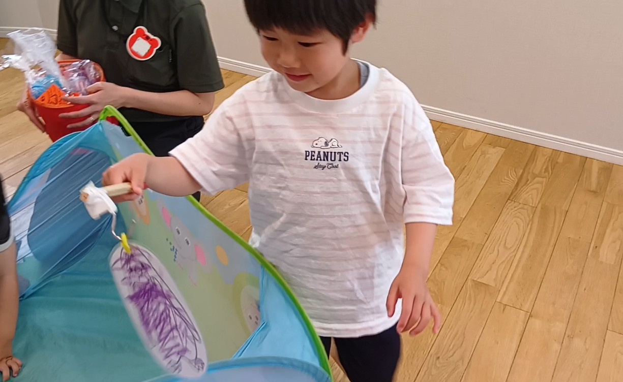 一人の子どもが、割りばしの釣り竿で制作した魚を釣っている。