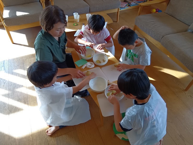 子どもたちはまな板の上でじゃがいもを皮を手で剥こうとしている