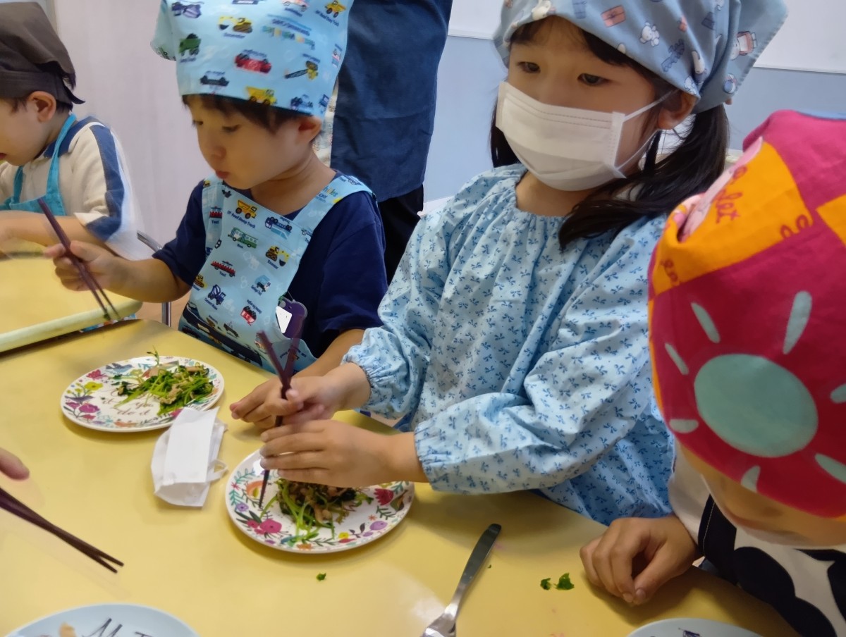 一人の子どもが片手で箸を持ち、反対の手で箸を動かそうとしている