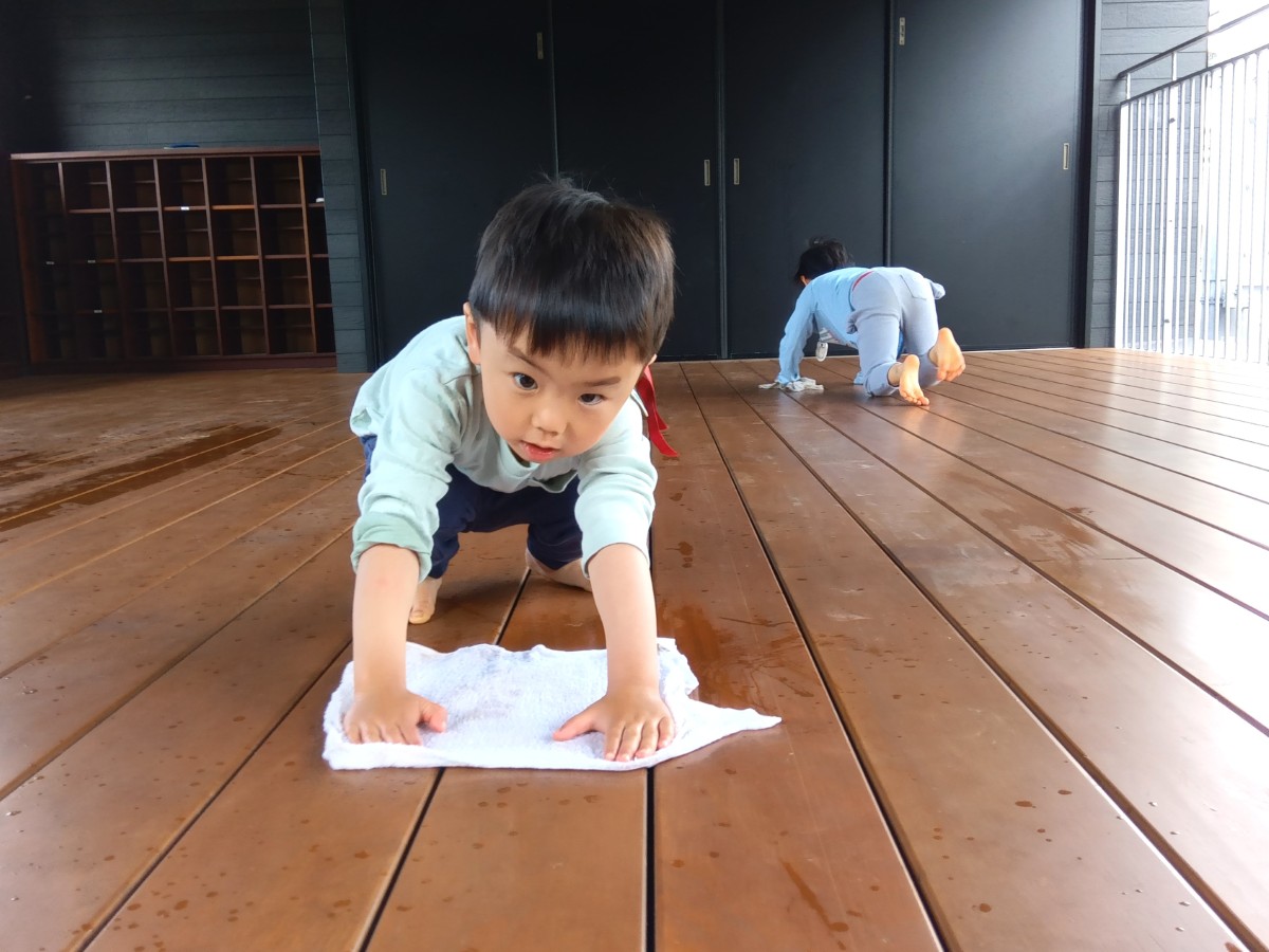 二人の子どもがテラスを雑巾がけしている