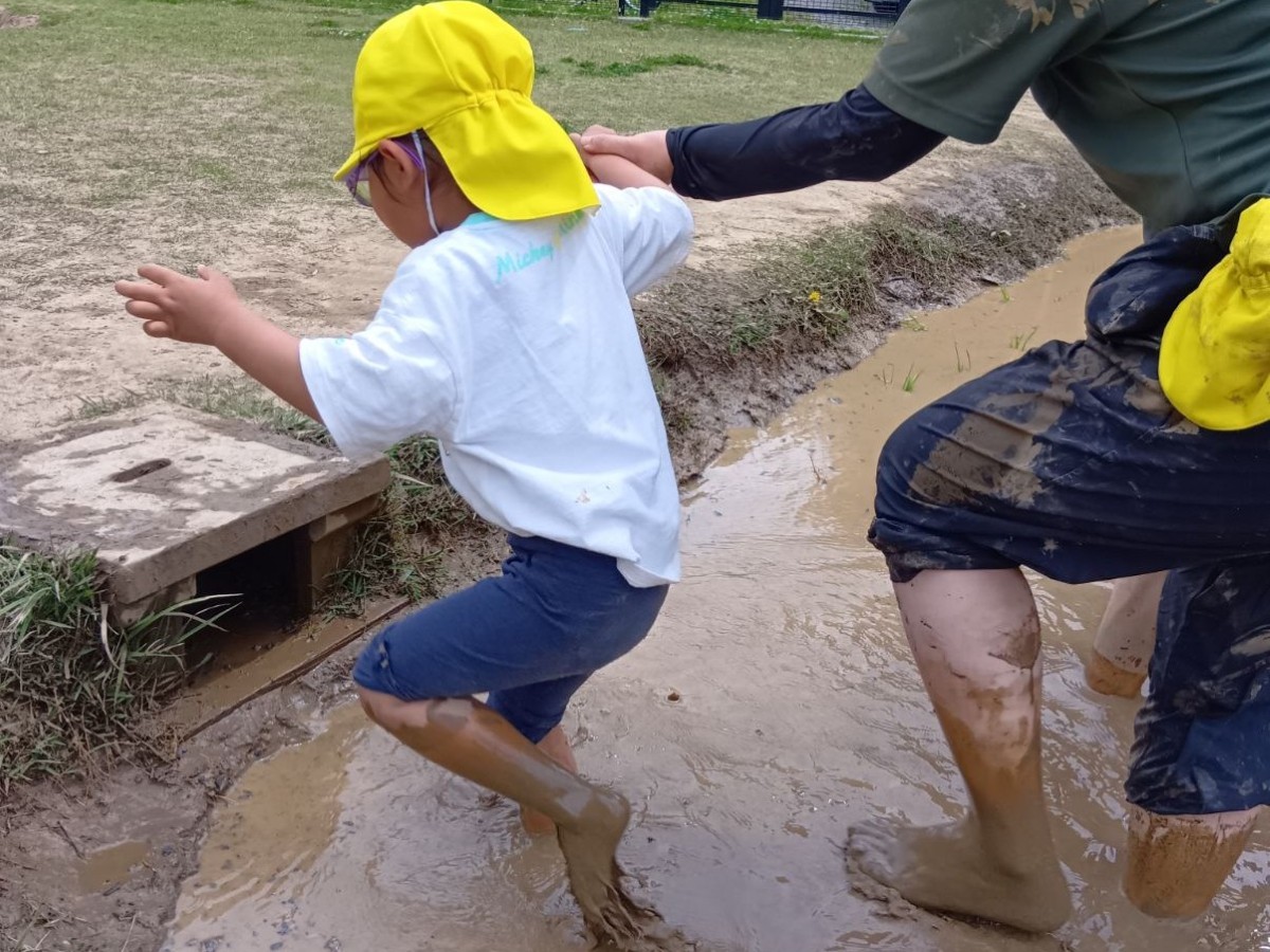 大人と子どもが手をつなぎ、田んぼから出ようとしている。