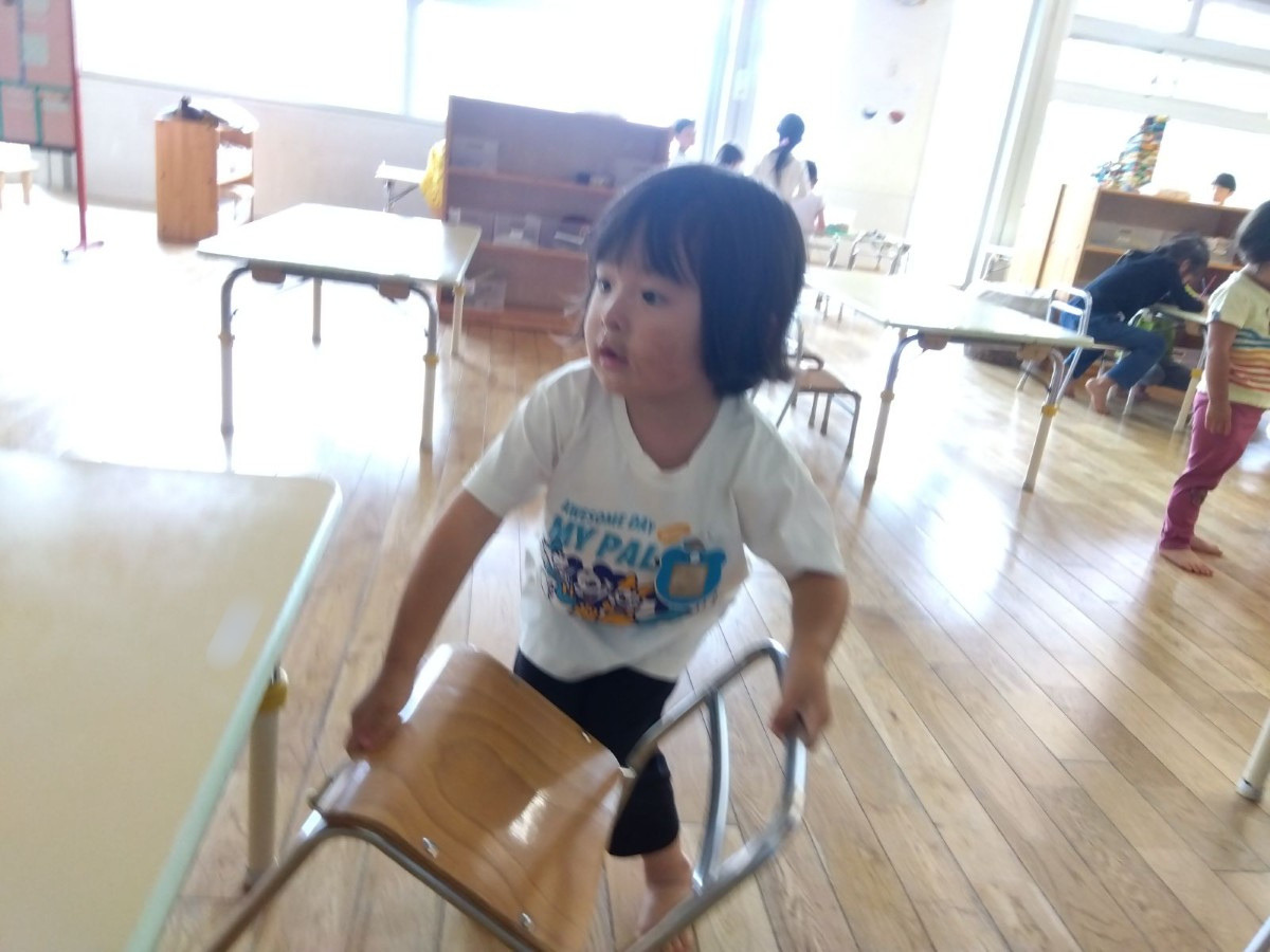 一人の子どもが椅子を横から持って運ぼうとしている。