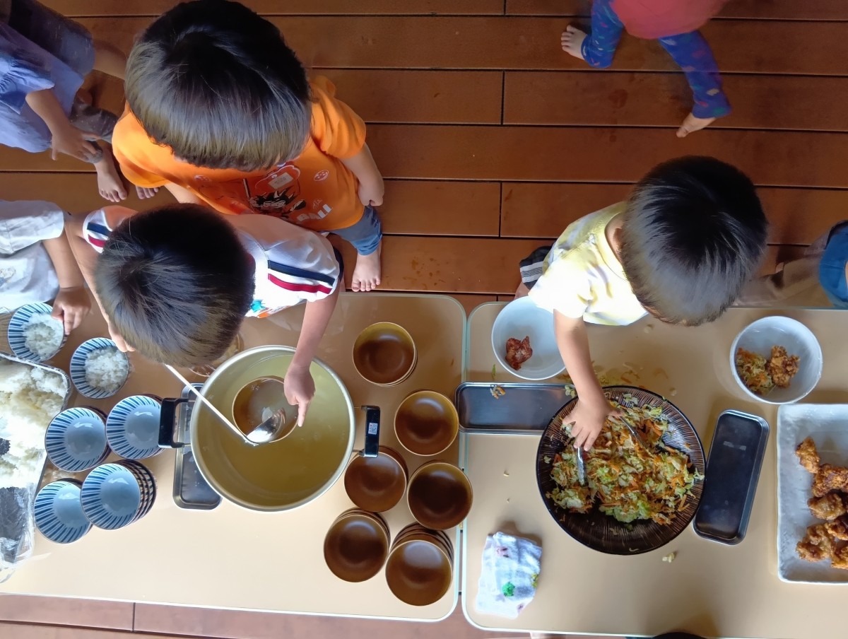 子どもたちは、長机の上に置かれた汁物や副菜をお椀に自らよそっている。